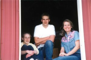 A picture of Kari and her children sitting in a barn.